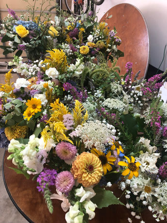 Assortment of colorful flowers, including yellow, white, and purple, arranged in a bouquet