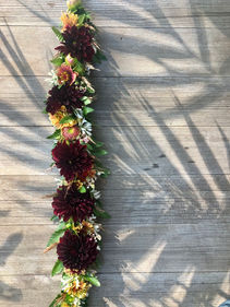 Burgundy and yellow flower lei on a wooden background