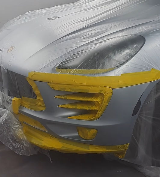 The front end of a Porsche Macan that has been taped and resprayed to fix a small scuff on the bumper.