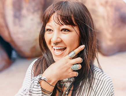 Young happy boho woman, with piercings and tattoos, smiling on beach.
