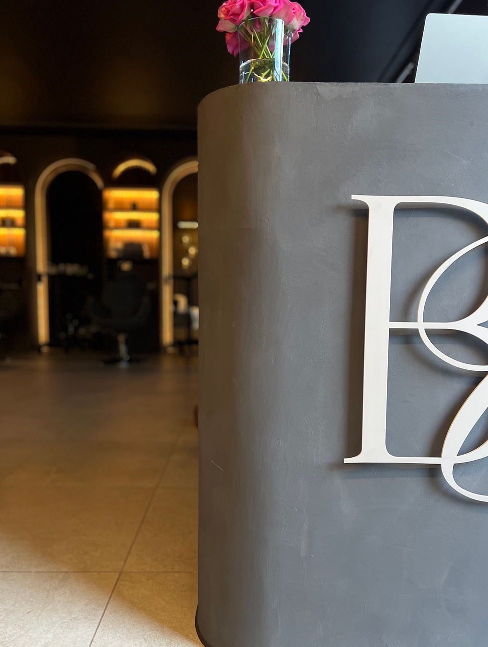 Curved Venetian plaster reception desk with Brows & Co branding