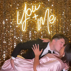 Bride and groom sharing a photo together in front of neon sign