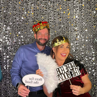 Couple wearing crown props in front of silver sequin backdrop