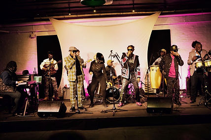 Large group of musical performers on an outdoor stage.