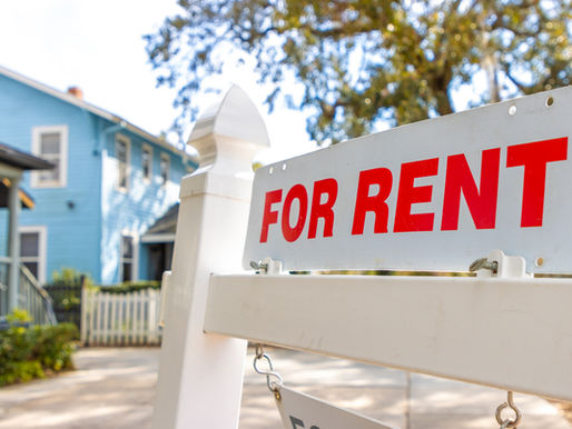 For Rent sign in front of a residential house on a sunny day, representing a rental property being prepared for summer tenants.