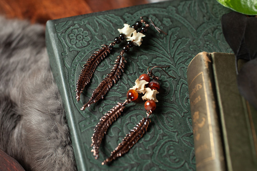 Flat lay of copper fern and bone earrings with gemstones