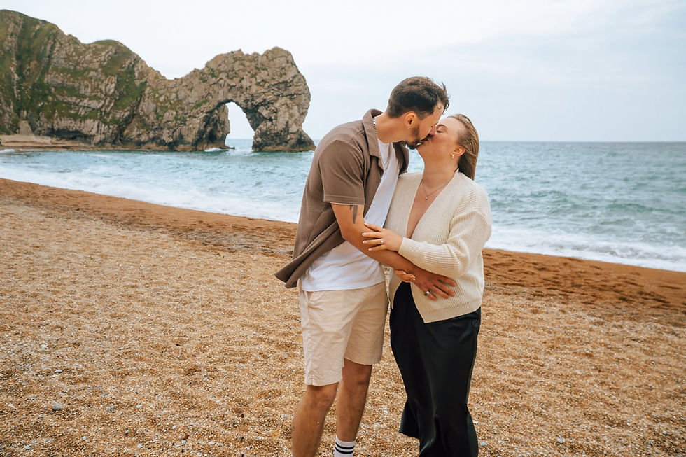 Couple kissing on the beach at Durdle Door, Dorset, during a natural engagement and proposal photography session.