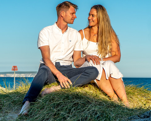 Relaxed engagement photos of couple sitting on Hengistbury Head beach in Dorset during pre-wedding photoshoot