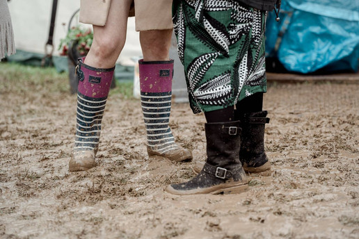 Close-up of two guests wearing muddy wellies at outdoor wedding.