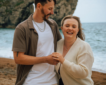 Couple standing on beach near Durdle Door during engagement photoshoot in Dorset