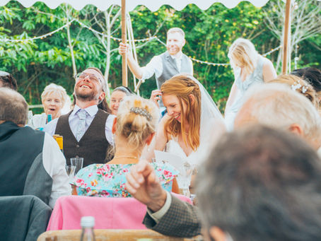 Bride and guests laughing during wedding speeches at marquee reception – hybrid Dorset wedding photographer and videographer.