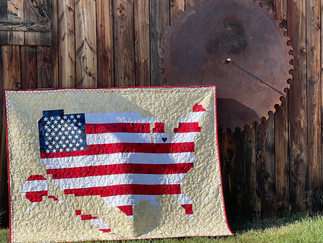 US quilt with barn in background