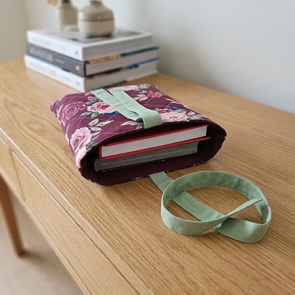 Thumbnail: quilted maroon floral book sleeve with ribbon tie closure protecting a hardcover book