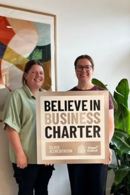 Two people smiling with Believe In Business Charter Silver Accreditation sign