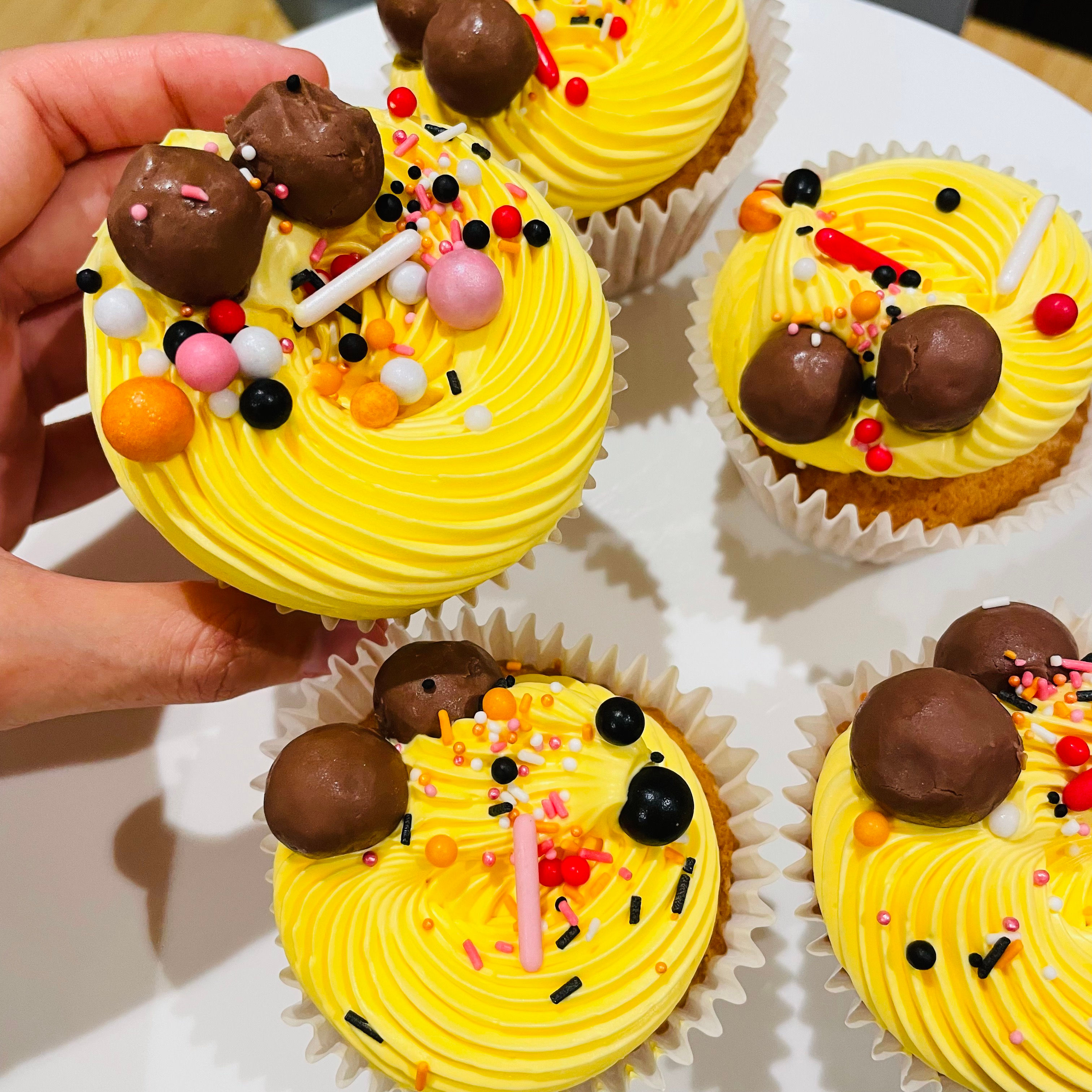 Photo of banana and chocolate chips cupcakes frosted with chocolate fudge buttercream and decorated with chocolates