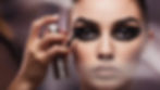 A makeup artist spraying setting spray on a model's face, with a focus on her eye makeup. The look is complete with a well-blended smokey liner.