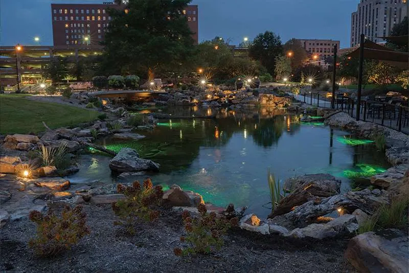 An outdoor water feature at night designed by Knob Hill Landscape Company of Illinois. 