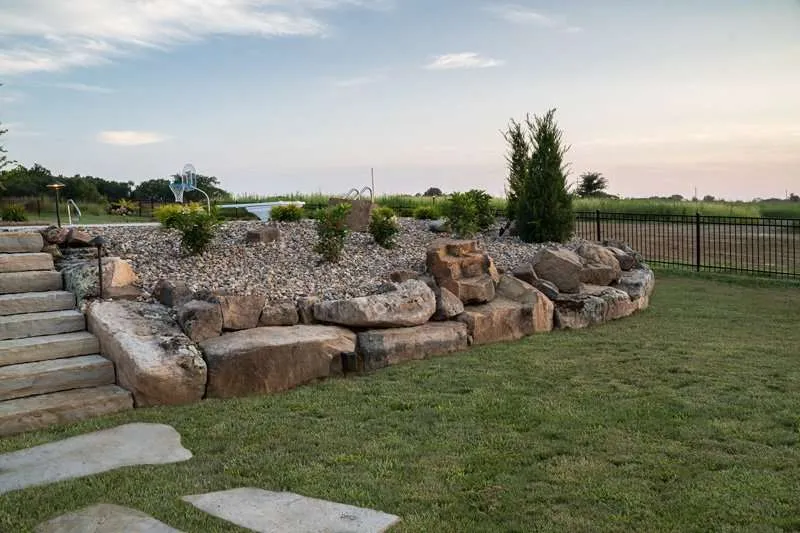 A large patio space for a modern residential home with seating, concrete patio pavers, and flowering plants designed by Knob Hill Landscape Company in Springfield, Illinois.