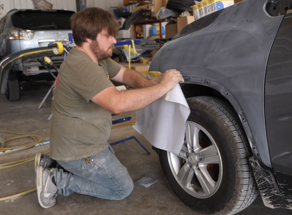 Employee of Phoenix Collision of Springfield, Illinois prepping a damaged vehicle for auto body restoration services.