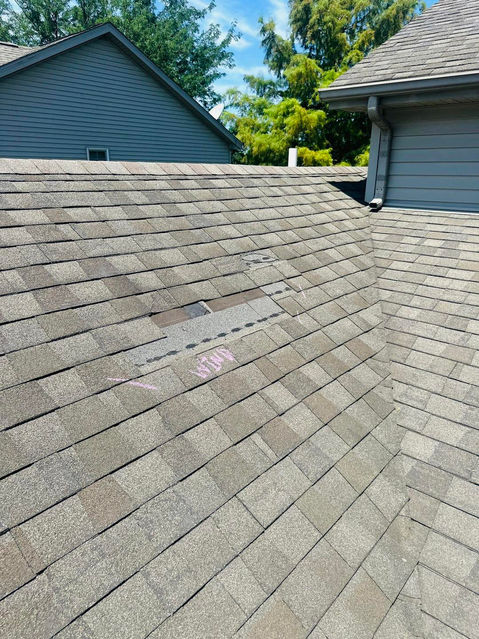 Copper Creek Contractors employee on top of a roof doing an inspection for a Bloomington, Illinois residential home after storm damage.