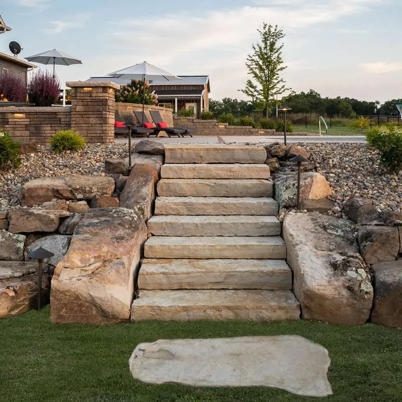 A large patio space for a modern residential home with seating, concrete patio pavers, and flowering plants designed by Knob Hill Landscape Company in Springfield, Illinois.