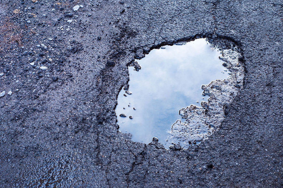 Pothole on an asphalt surface full of ponding water and eroding the edges of the pothole. Repairs by The Road Doctor.
