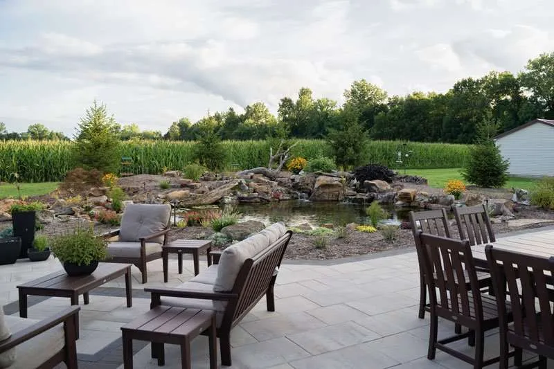 A patio space with a fireplace and seating built in a residential backyard by Knob Hill Landscaping Company in Springfield, Illinois. 