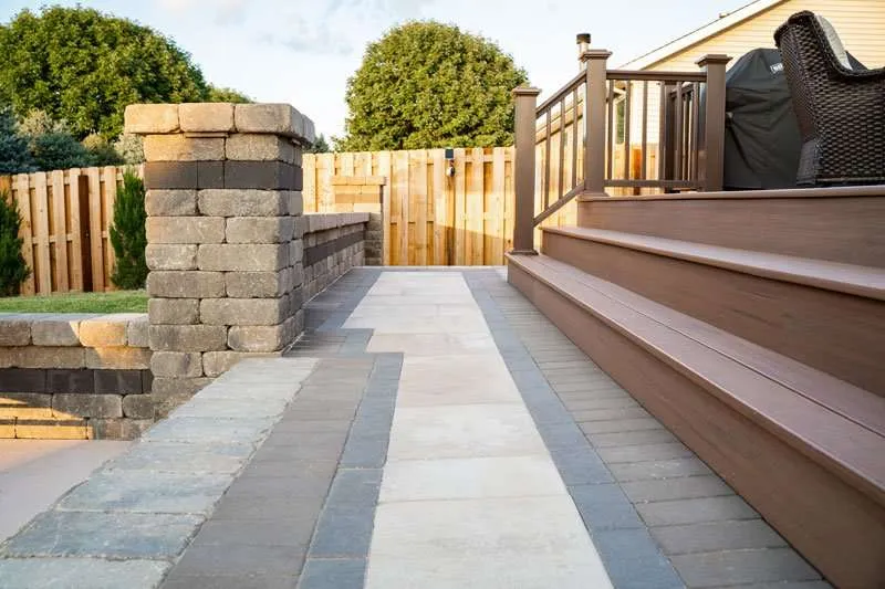 A closeup photo of a set of stone pavers crafted into steps to align with wooden stairs from a deck. Space designed by Knob Hill Landscape Company of Springfield, Illinois. 