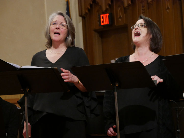 Two women singing at podiums for the Springfield Choral Society