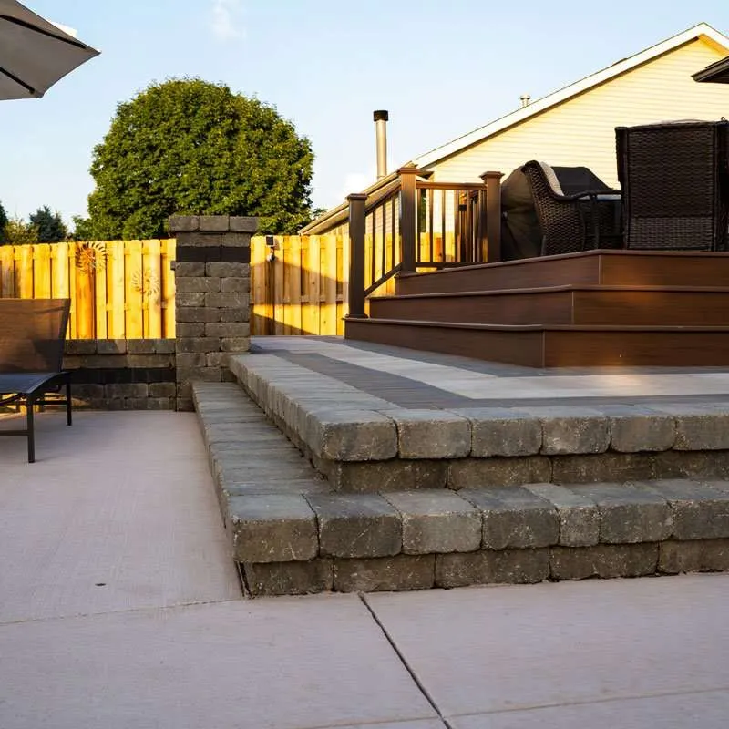 A closeup photo of a set of stone pavers crafted into steps to align with wooden stairs from a deck. Space designed by Knob Hill Landscape Company of Springfield, Illinois. 
