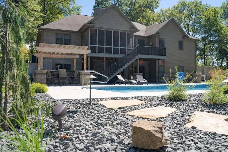 A large modern home with backyard landscaping, a patio, and inground pool designed by Knob Hill Landscaping Company of Springfield, Illinois. 