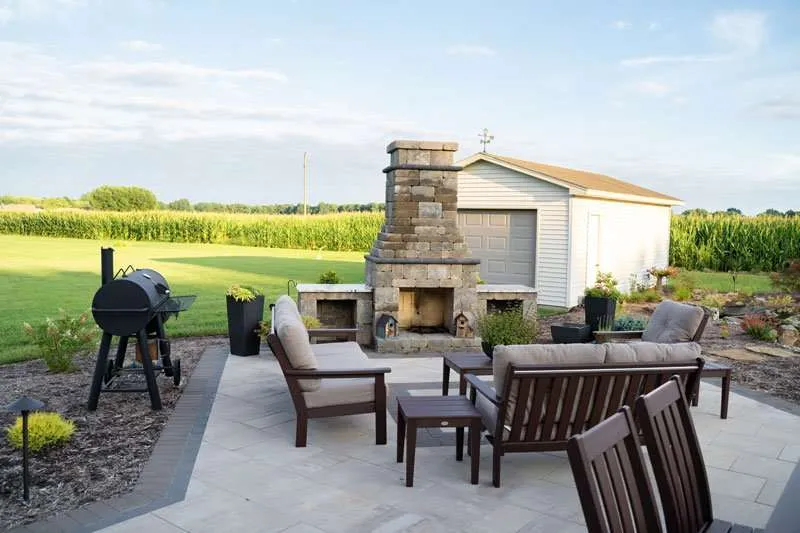 A patio space with a fireplace and seating built in a residential backyard by Knob Hill Landscaping Company in Springfield, Illinois. 