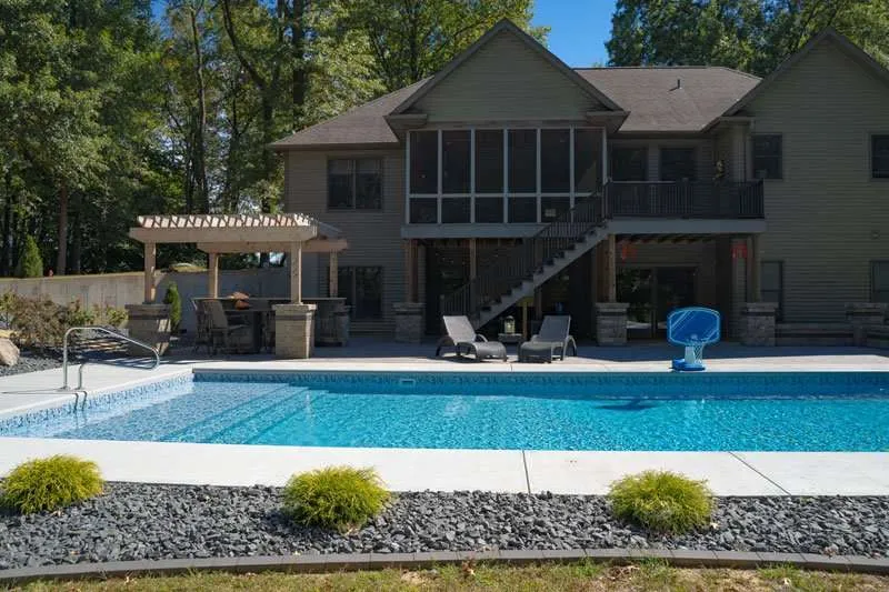 A large modern home with backyard landscaping, a patio, and inground pool designed by Knob Hill Landscaping Company of Springfield, Illinois. 