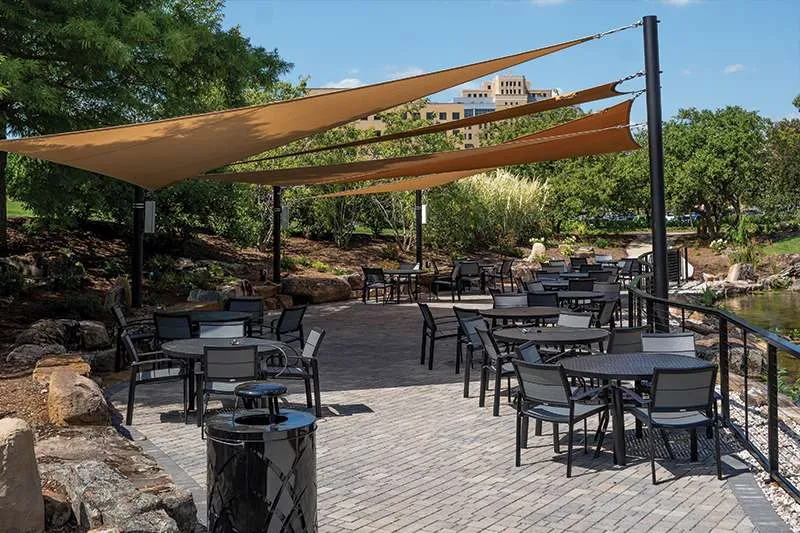 A large patio with shade sails for a commercial building rest area designed by Knob Hill Landscape Company of Illinois. 
