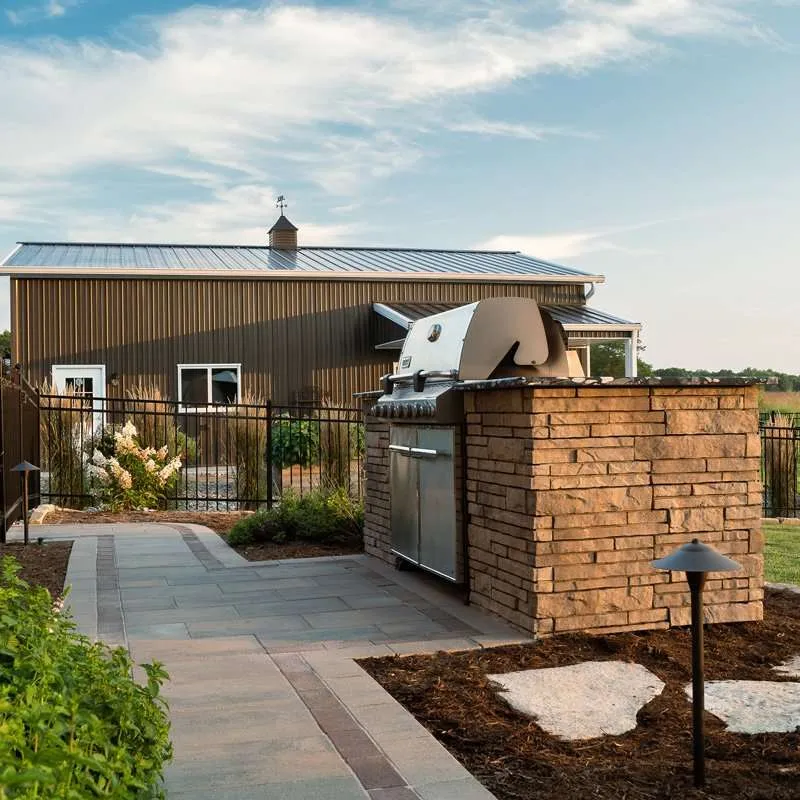 A large patio space for a modern residential home with seating, concrete patio pavers, and flowering plants designed by Knob Hill Landscape Company in Springfield, Illinois.