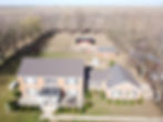 Arcola, IL farmhouse with shed in the background and large fenced in area for farm animals. Brick home in the foreground with small bushes surrounding the home.