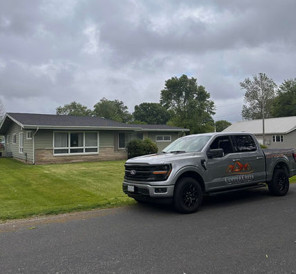 Copper Creek Contractors of Champaign, Illinois branded truck in front of a residential home for a roof replacement.