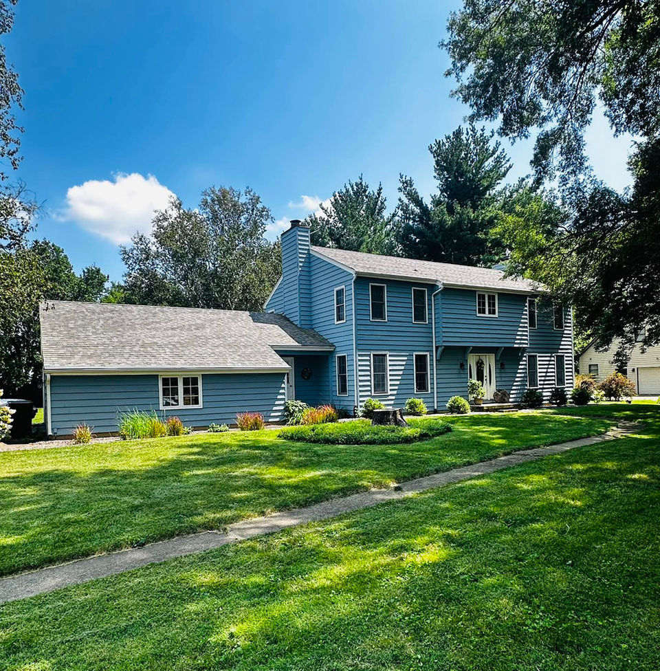 A large residential home with blue siding and a new roof installed by Copper Creek Contractors of Champaign, IL.