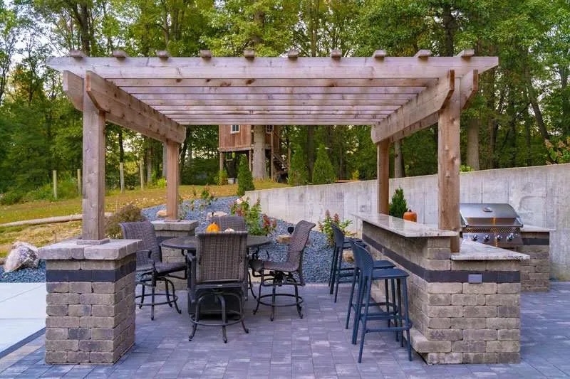 Backyard patio with a pergola above a seating area. Space designed by Knob Hill Landscaping Company in Springfield, Illinois. 