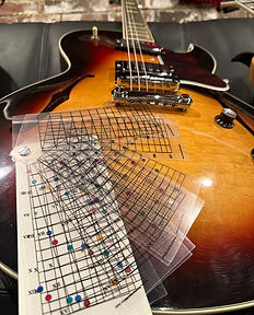 Guitar lying on its back with the Clearstring Guitar Chord Finder on top of it.