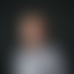 A man with a black checkered button up shirt on a dark grey background.