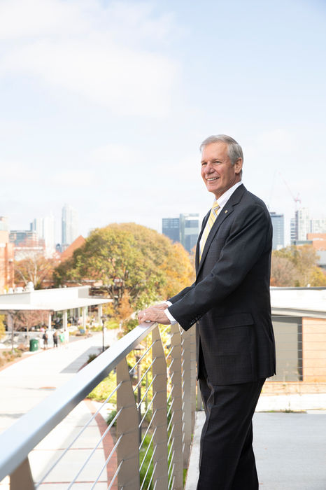 Man in suit smiling on balcony overlooking city