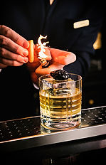 Un cocktail haut de gamme est préparé à table par un barman, offrant une touche raffinée de mixologie française. Ce moment gourmand s'inscrit dans le cadre de l'expérience immersive du dîner VIP AI ON US, où les leaders de la politique et de l'innovation en IA se rencontrent autour d'un repas raffiné.