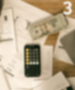 Overhead view of a desk with financial charts, a smartphone calculator, and a stack of $20 bills; large white 3 at top right.