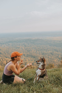 a girl blowing a dandelion in her dog's face