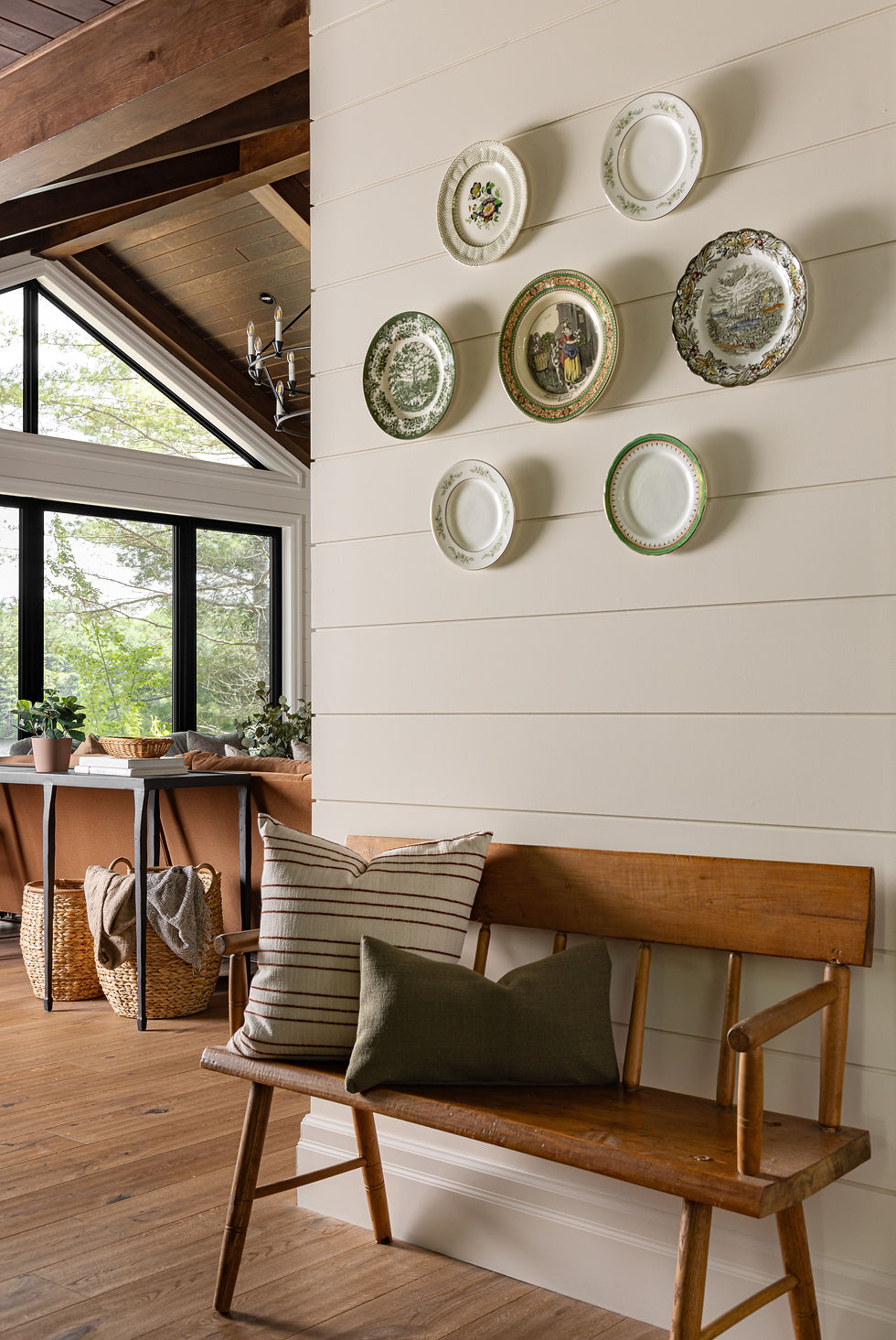 Cottage dining nook with shiplap walls, curated vintage plates, and rustic wood bench