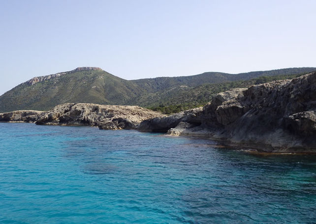 Green Moutti tis Sotiras peak in the background. Light blue water in the foreground, and then the Akamas north rocky coastline.