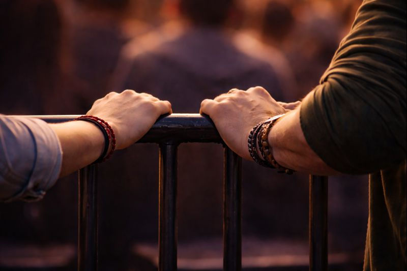 A man and a woman's hands holding on to a bar almost touching each other.