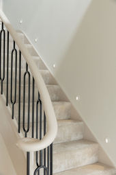 Carpeted staircase with curved handrail and black balusters