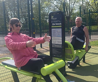 Woman and man exercising on outdoor gym equipment